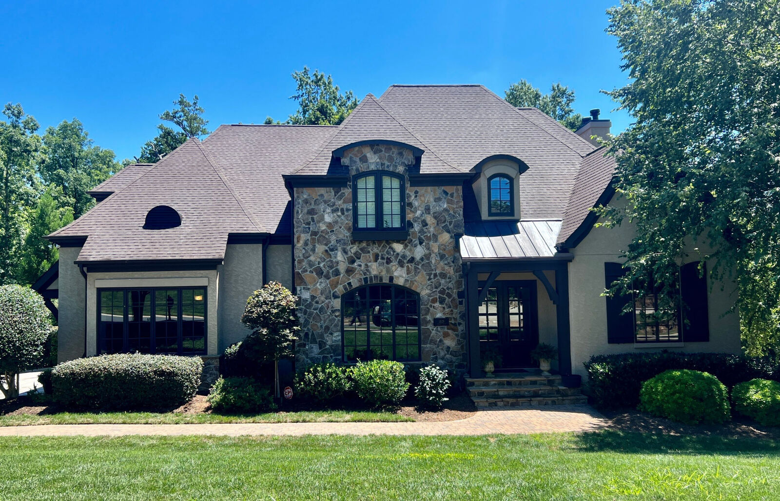 Stone-front home with a dark shingle roof